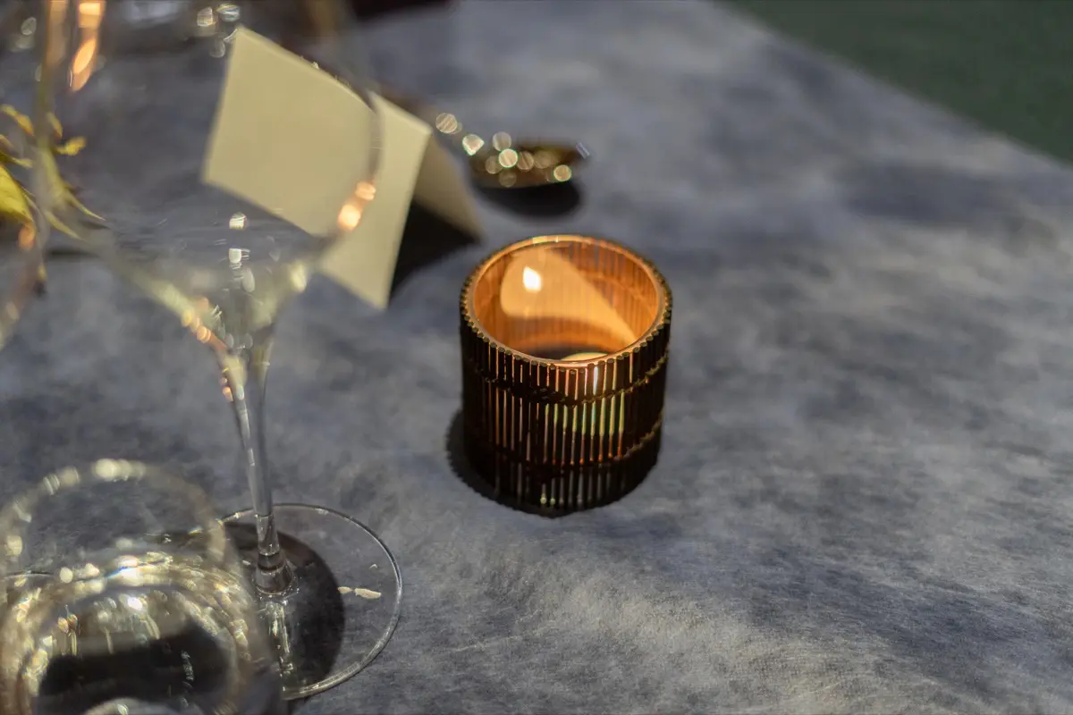 A candle, glasses and a place card on a dinner table