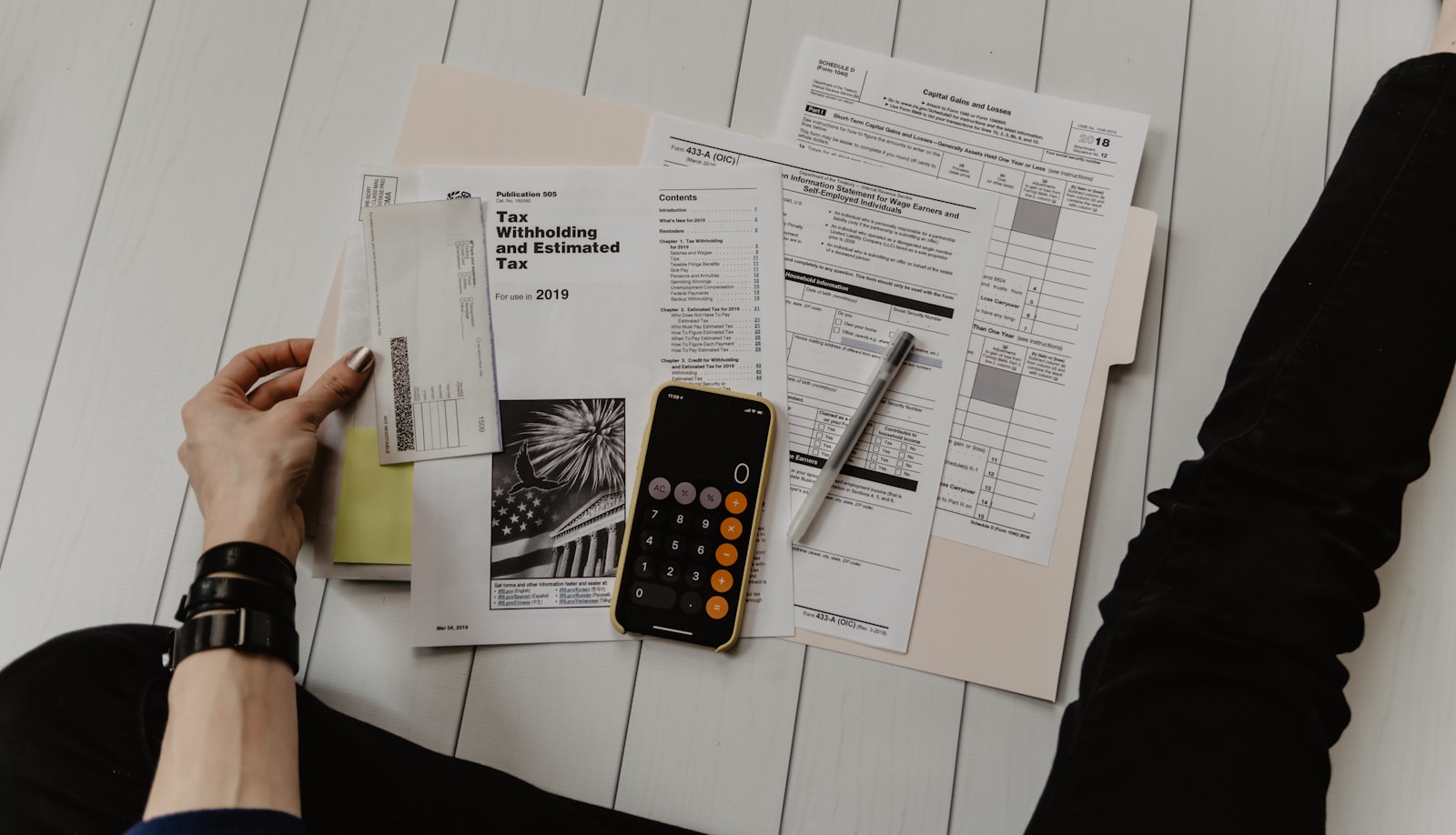 Hands reviewing financial statements with a calculator and pen on a white desk