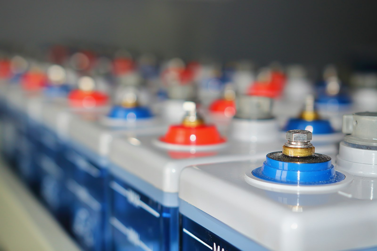 Rows of stationary battery cells with red and blue terminals in a grid-scale storage installation