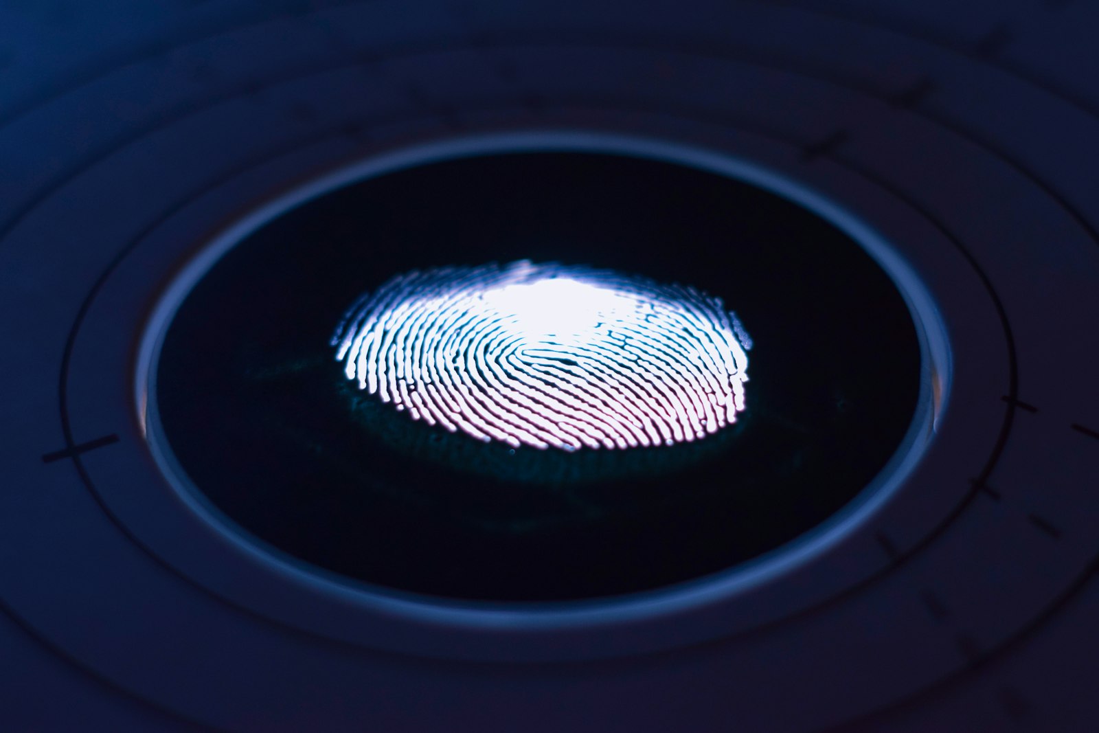 A fingerprint glowing on a dark biometric scanner