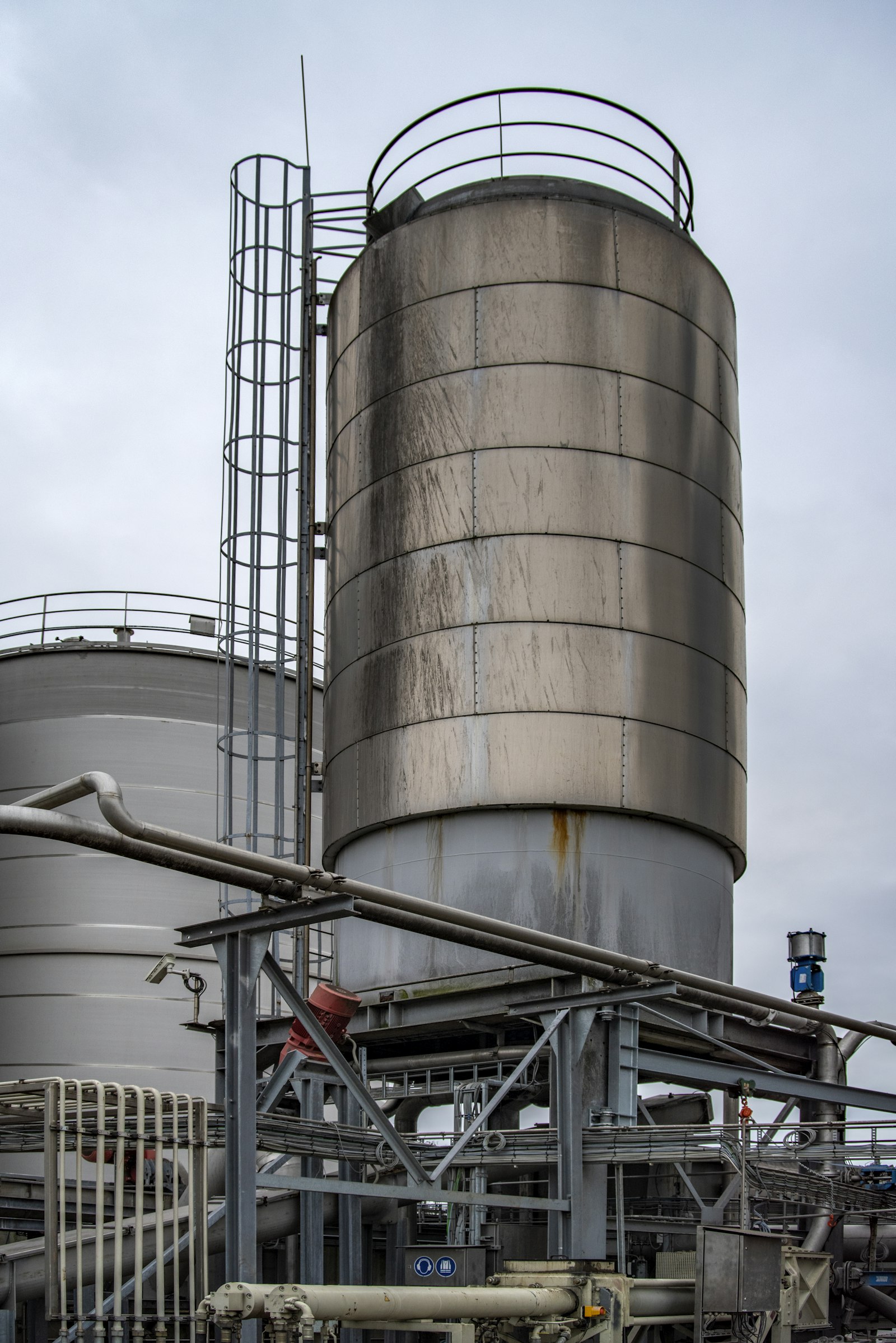 Industrial storage tanks and pipework at a chemical plant under an overcast sky