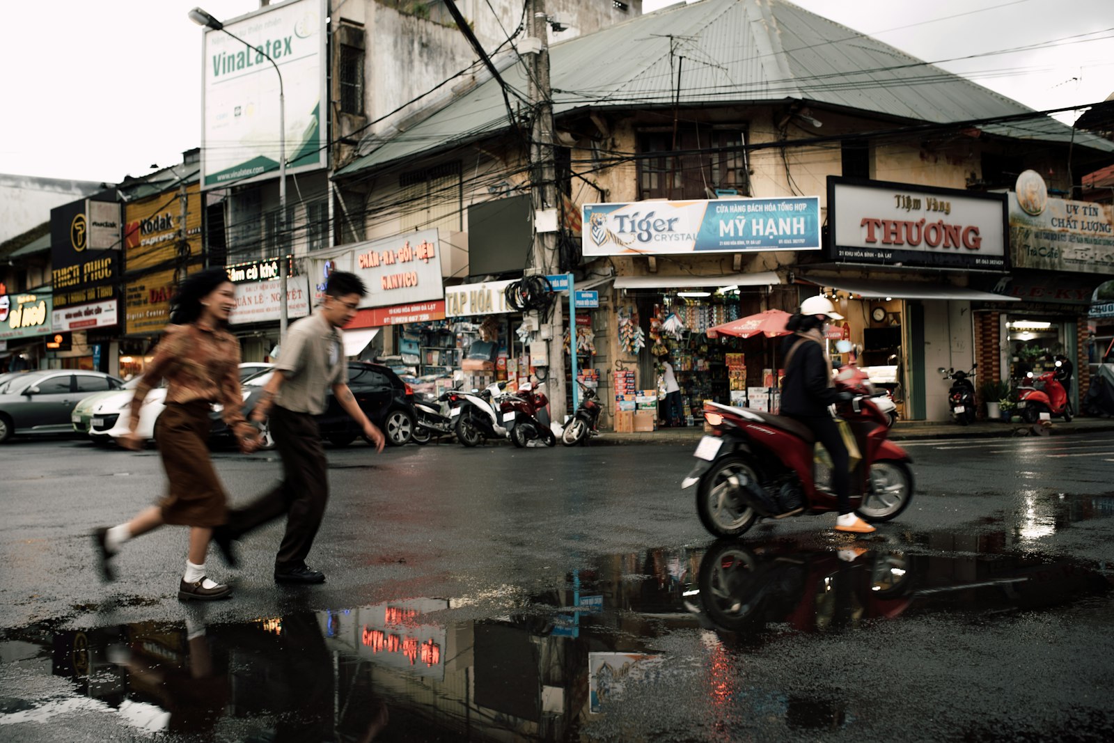 Pedestrians crossing a flooded street in a Southeast Asian city after heavy rain