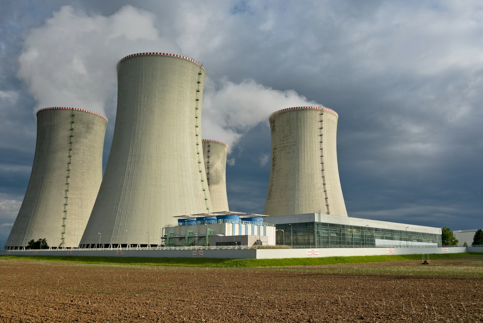 Cooling towers of a nuclear power plant releasing steam above farmland