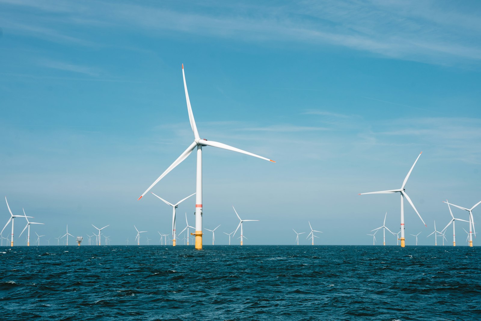 Offshore wind turbines standing in open sea under a blue sky