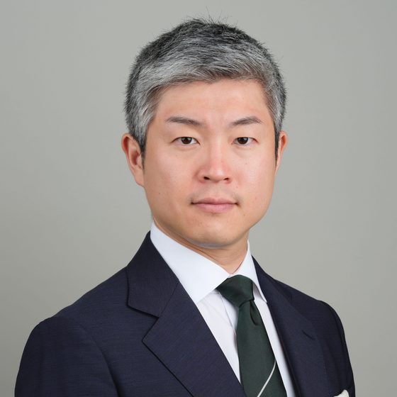 Shuhei Azuma, former mayor of Shijōnawate City and Executive Vice President of SLE Energy, in a navy suit against a neutral grey background