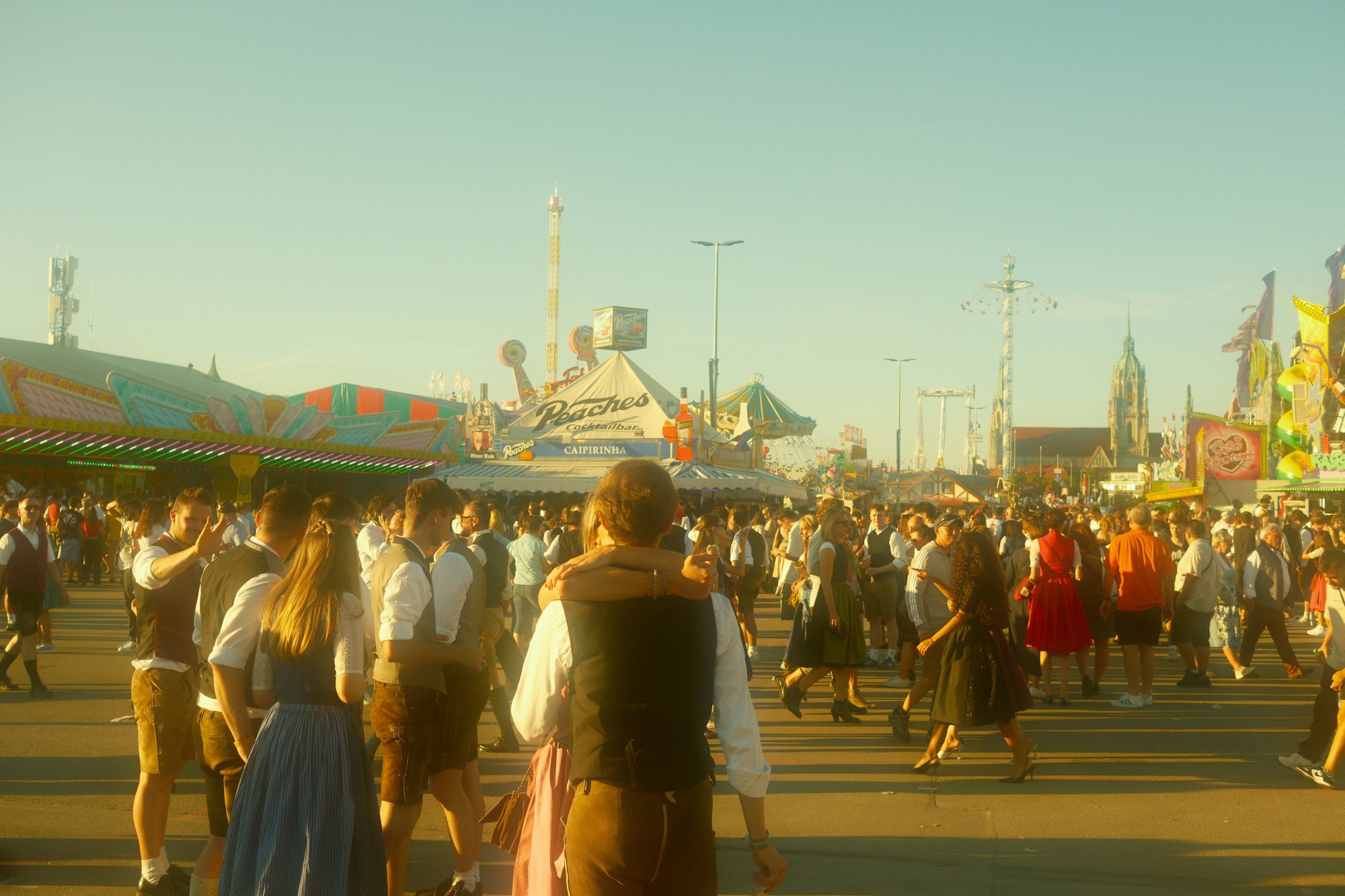 Crowds in traditional Bavarian dress on the avenue at Munich’s Oktoberfest, in golden-hour light.